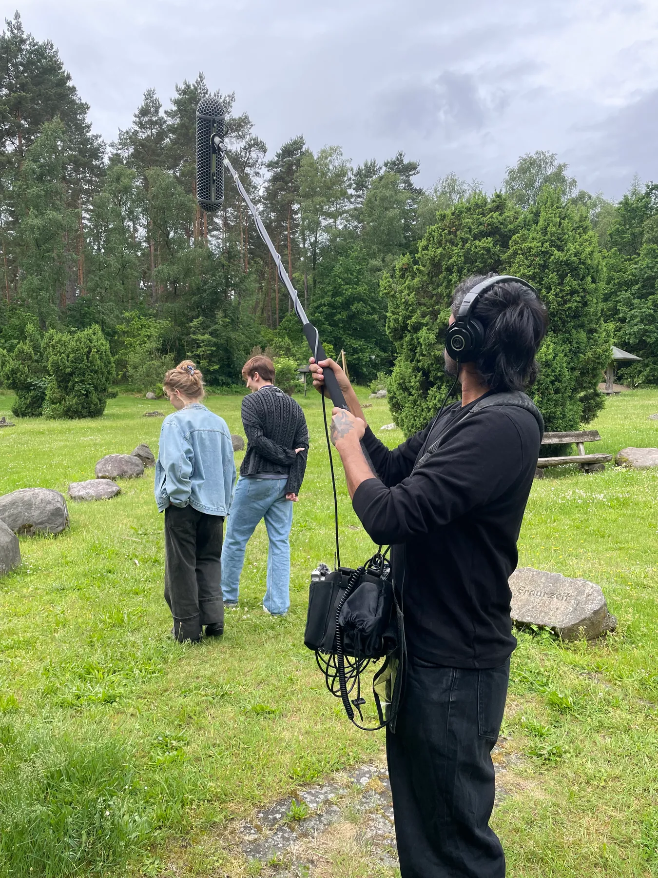 Akshay Gite operating a boom microphone and field recorder on an outdoor film set