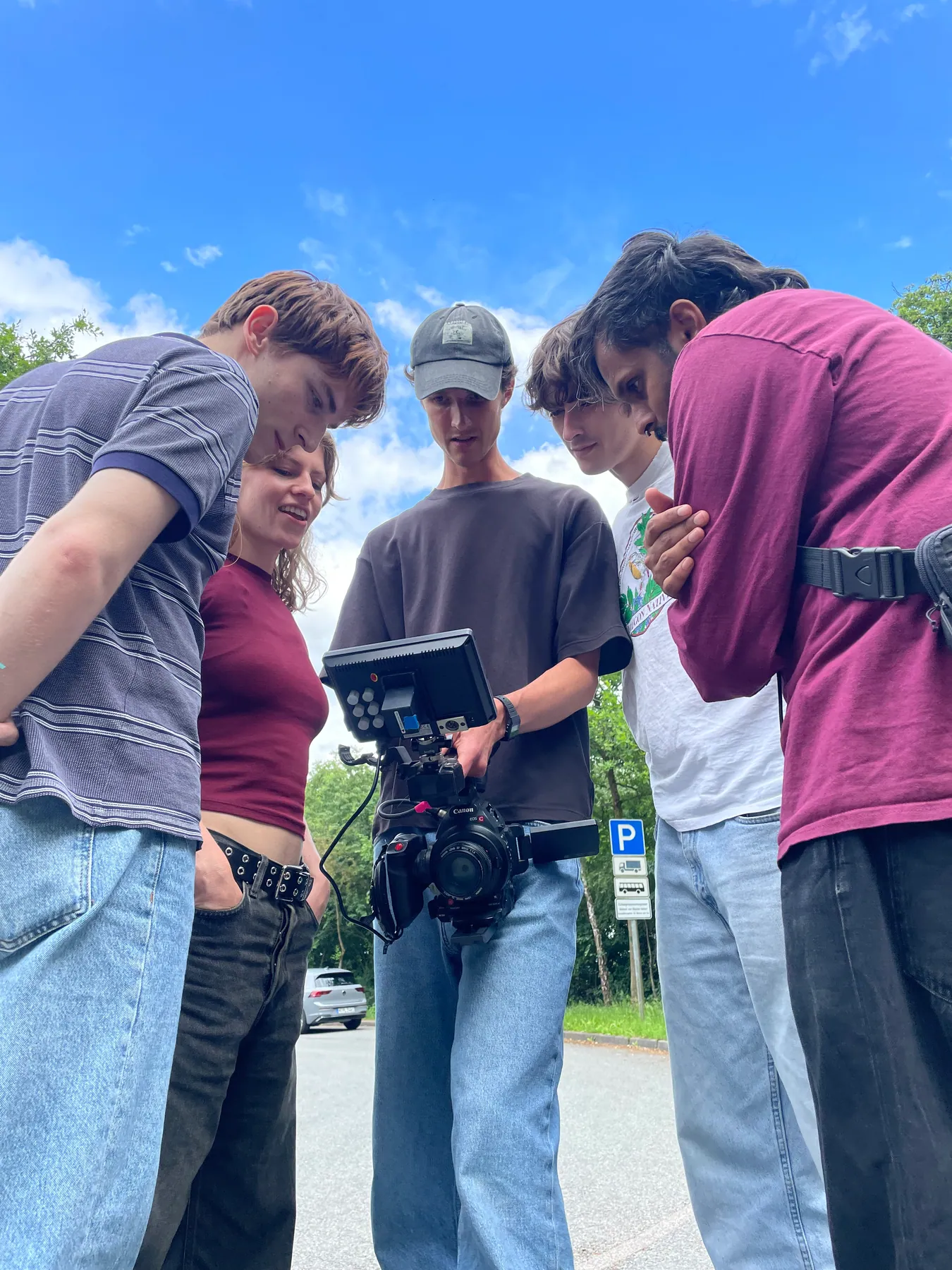 A small film crew reviewing a camera setup outdoors