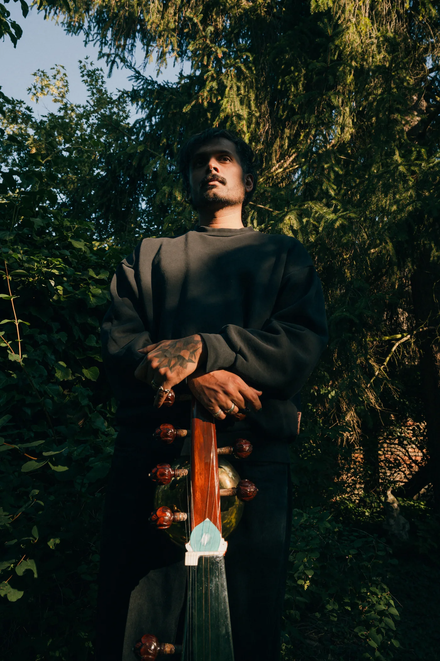 Akshay Gite holding a sarod among trees