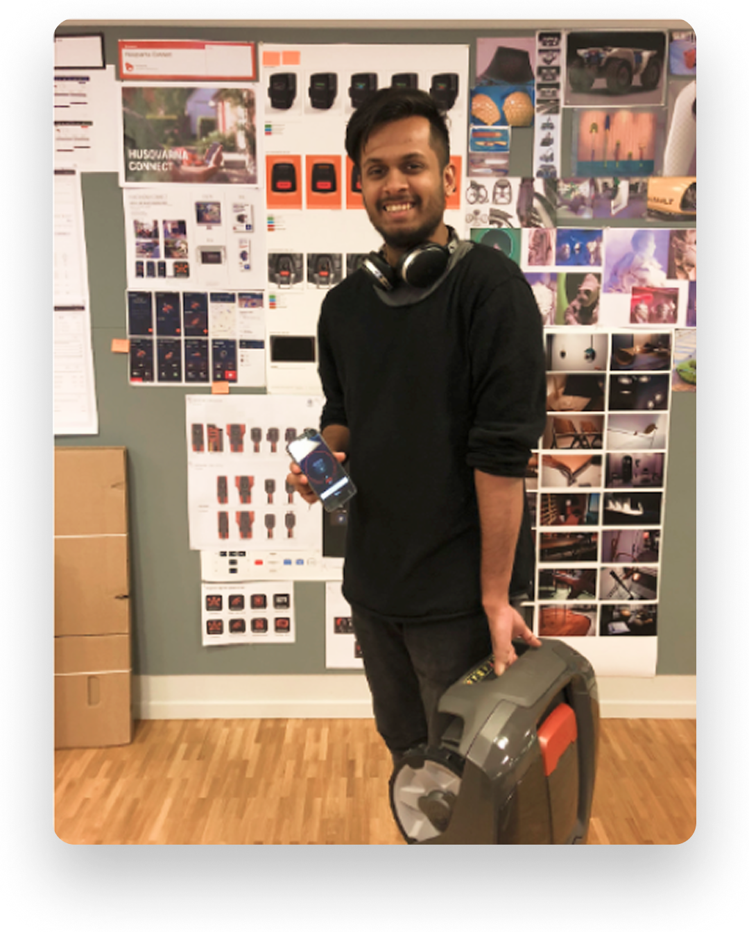 Designer holding a Husqvarna mower in front of a project moodboard wall